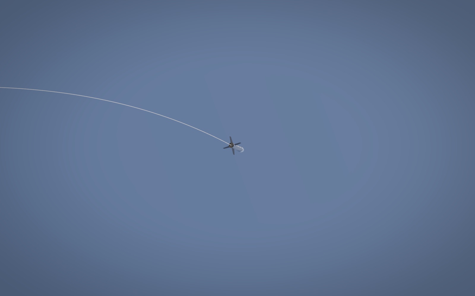 The rocket seen from the ground, high in the sky, with its trail curving over.